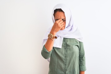 Young beautiful Arab woman wearing traditional Muslim hijab over isolated background tired rubbing nose and eyes feeling fatigue and headache. Stress and frustration concept.