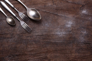 old silver spoon and fork on wooden background