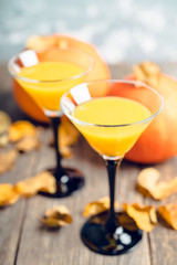 Autumn cocktail with pumpkin and orange juice in martini glass on the rustic background. Selective focus. Shallow depth of field.