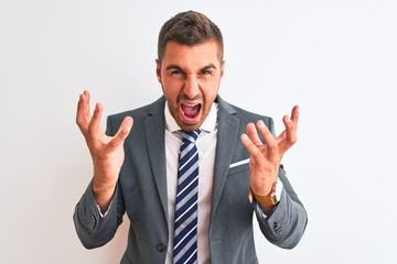 Young handsome business man wearing suit and tie over isolated background crazy and mad shouting and yelling with aggressive expression and arms raised. Frustration concept.