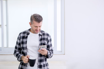 Caucasian man using a phone while holding coffee