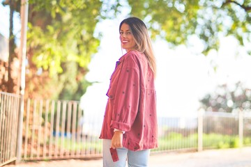 Young beautiful woman wearing red jacket smiling happy and confident. Standing with smile on face at the town street