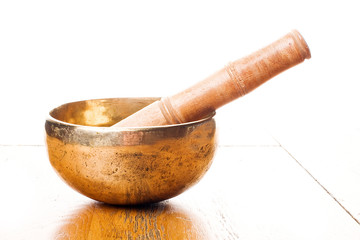 Closeup of a singing bowl and its mallet on a wooden table