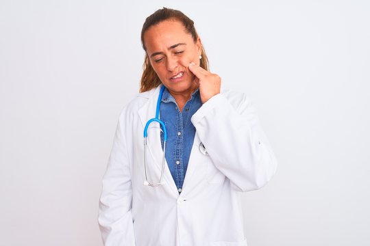 Middle age mature doctor woman wearing stethoscope over isolated background touching mouth with hand with painful expression because of toothache or dental illness on teeth. Dentist concept.