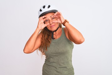 Middle age mature cyclist woman wearing safety helmet over isolated background Trying to open eyes with fingers, sleepy and tired for morning fatigue