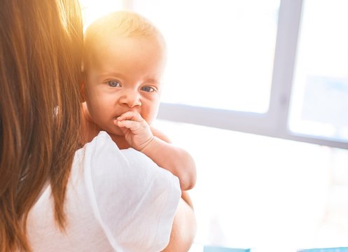 Young beautifull woman and her baby standing at home. Mother holding and hugging newborn