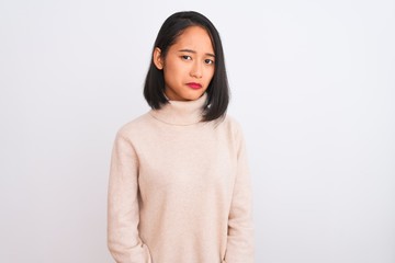 Young chinese woman wearing turtleneck sweater standing over isolated white background depressed and worry for distress, crying angry and afraid. Sad expression.