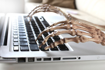 Close up of skeleton typing on laptop 