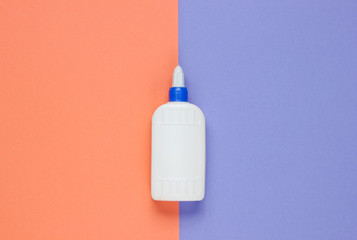 Bottle of glue on a color studio paper background. Top view