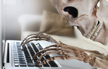 Close up of skeleton typing on laptop 