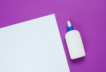 Bottle of glue on a purple paper background with white space. Top view