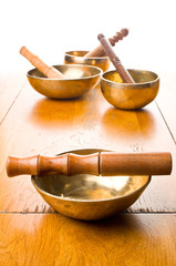 Closeup of four singing bowls and their mallets on a wooden table