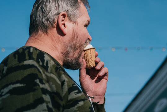 Portrait of a man close-up eating ice cream on the background of the city. The lower point shooting