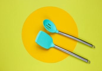 Kitchen tools on green background with a yellow circle in the middle. Minimalistic kitchen still life. Top view