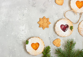 Linzer Christmas or New Year cookies filled with red and orange jam and dusted with sugar on light grey stone background. Traditional Austrian Christmas cookies. Festive decoration. 