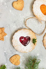 Linzer Christmas or New Year cookies filled with red and orange jam and dusted with sugar on light grey stone background. Traditional Austrian Christmas cookies. Festive decoration. 