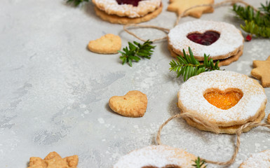 Linzer Christmas or New Year cookies filled with red and orange jam and dusted with sugar on light grey stone background. Traditional Austrian Christmas cookies. Festive decoration. 