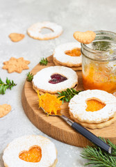 Jelly Christmas Linzer cookies with orange and red jam on a wooden board with festive decoration. Shortcrust pastry. 