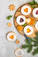 Jelly Christmas Linzer cookies with orange and red jam on a wooden board with festive decoration. Shortcrust pastry. 