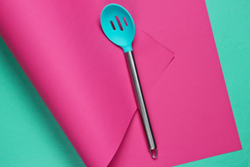 Kitchen spoon on wrapped paper background. Minimalistic cooking still life. Pastel color trend