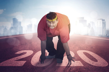 Overweight man kneeling on number 2020