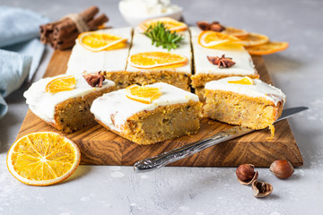 Carrot cake pieces with cream cheese frosting, decorated with dried orange fruit slices and anise. 