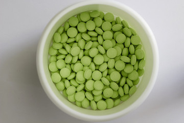green oval tablets in white jar in medical healthcare drugstore concept,closed up