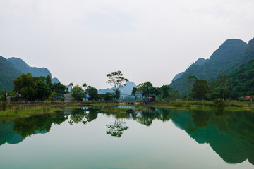 Fototapeta na wymiar Mountains reflected in an ember green lake on the hidden Cat Ba Island which is regularly visited by boat tours around Ha Long Bay