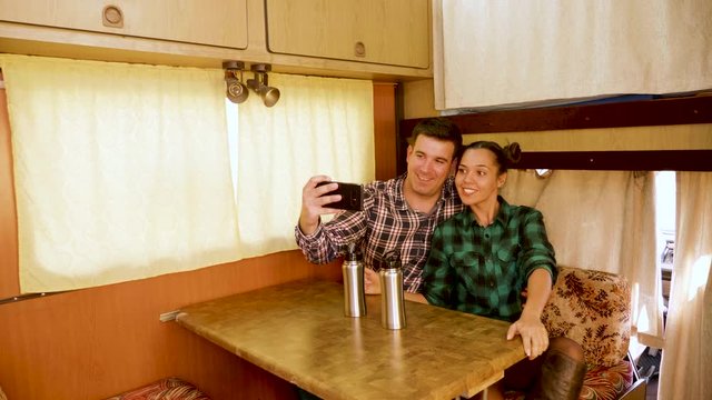 Beautiful young couple making a selfie inside of their retro camper van