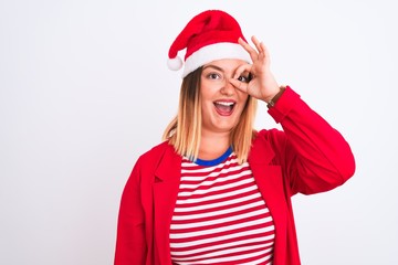 Young beautiful woman wearing Christmas Santa hat over isolated white background doing ok gesture with hand smiling, eye looking through fingers with happy face.