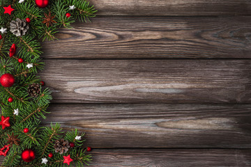 Merry Christmas and Happy New Year background. Fir tree branches with red holiday decorations on rustic wooden table