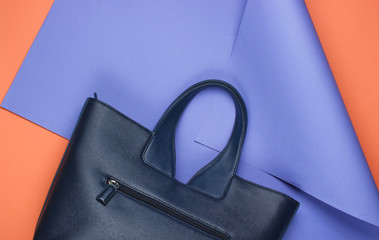 Leather bag on folded paper background. Minimalistic fashion still life. Flat lay. Top view