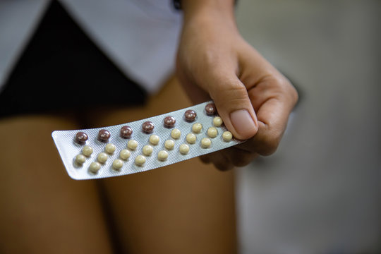 Asian woman holding contraceptive pills in the bed room Health and medical Gynecology hormone concept