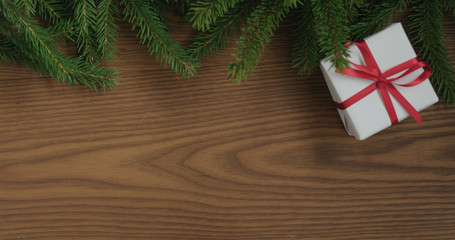 Top view gift box with red ribbon on ash surface table decorated with spruce twigs