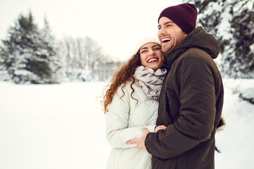 Young couple on the snow in winter in the park