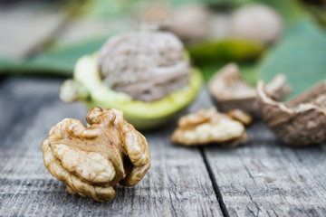 Obraz na płótnie Canvas Fresh walnuts in a green shell near the walnut kernel on an old wooden table. Nuts in green shells.