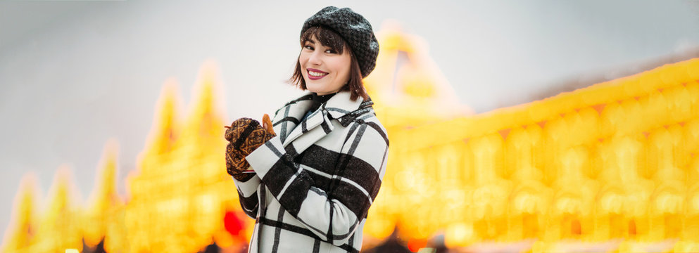 Image of smiling brunette in hat and checkered coat on winter walk