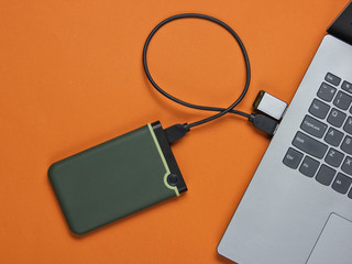 Laptop with flash drive, external hard drive. on brown paper background. Studio shot, top view.