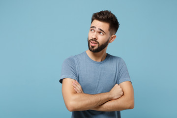 Young pensive handsome man in casual clothes posing isolated on blue background, studio portrait....