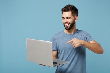 Young smiling attractive man in casual clothes posing isolated on blue wall background, studio...