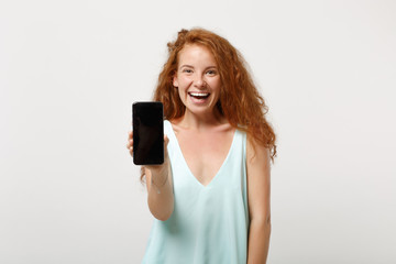 Fototapeta premium Young laughing redhead woman girl in casual light clothes posing isolated on white background, studio portrait. People lifestyle concept. Mock up copy space. Hold mobile phone with blank empty screen.