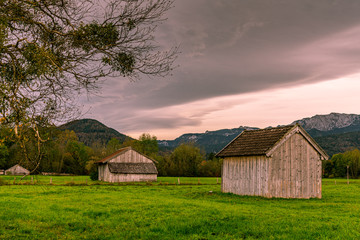 Zwei Holzhütten auf einer Weide in der Alpenregion