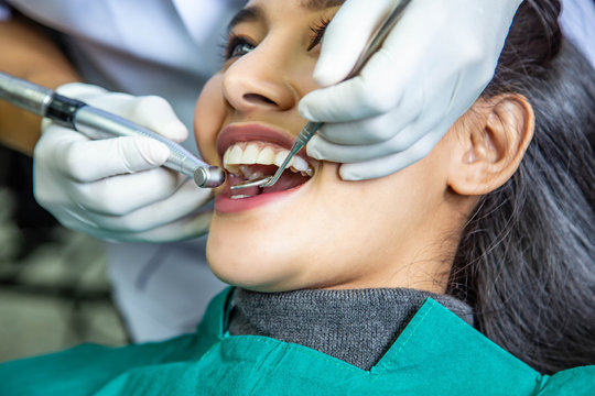 Dentist examining teeth of beautiful young smiling Asian woman in hospital clinic dental health care concept