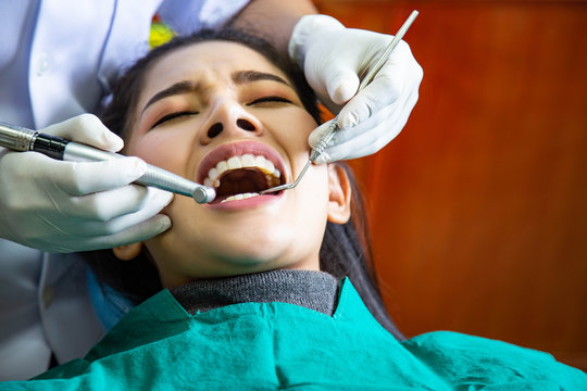 Dentist examining treat teeth of beautiful young Asian woman in hospital clinic dental health care concept