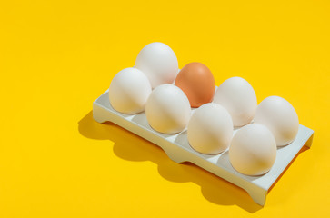 Tray with chicken eggs on yellow background. Minimalistic food concept.