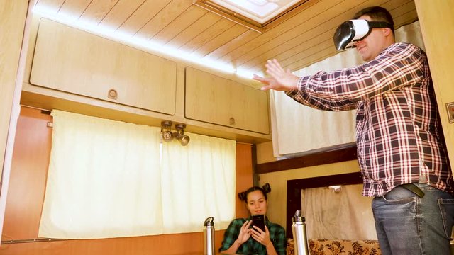 Boyfriend experiencing virtual reality goggles inside retro camper van