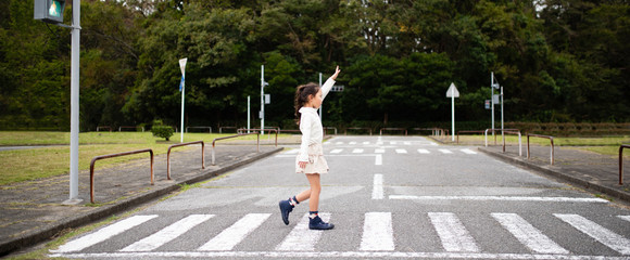 手を上げて横断歩道を渡る子供