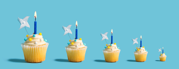 Big and small celebratory cupcakes with decorative lit candles