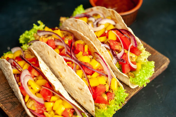 Mexican tacos with meat and vegetables on a stone background