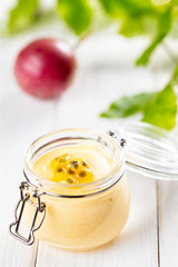 Obraz na płótnie Canvas Passion fruit mousse in glass jar on white wooden background, vertical composition
